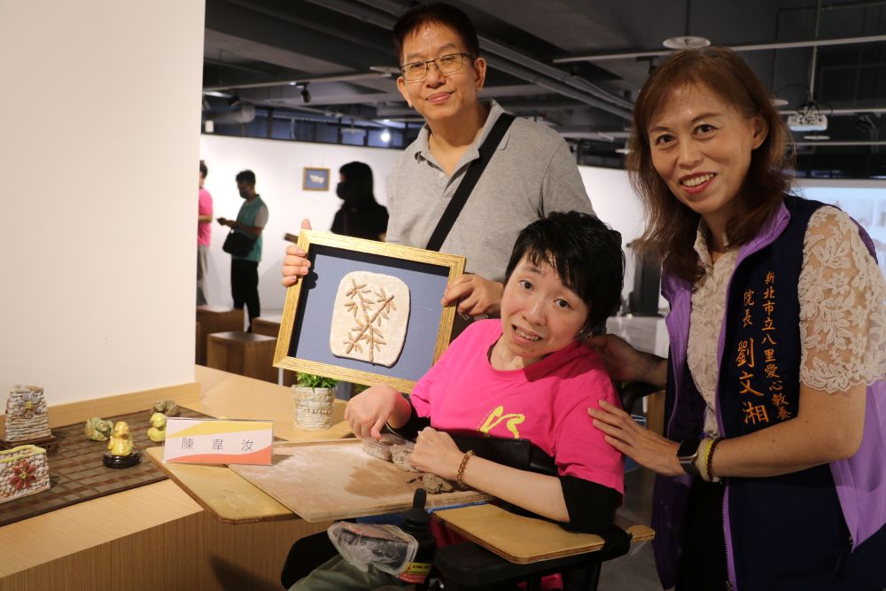 韋汝展出自己的作品黃色小鴨和綠頭鴨及竹子  左1為指導老師張耀全  右1為八里愛心教養院院長劉文湘