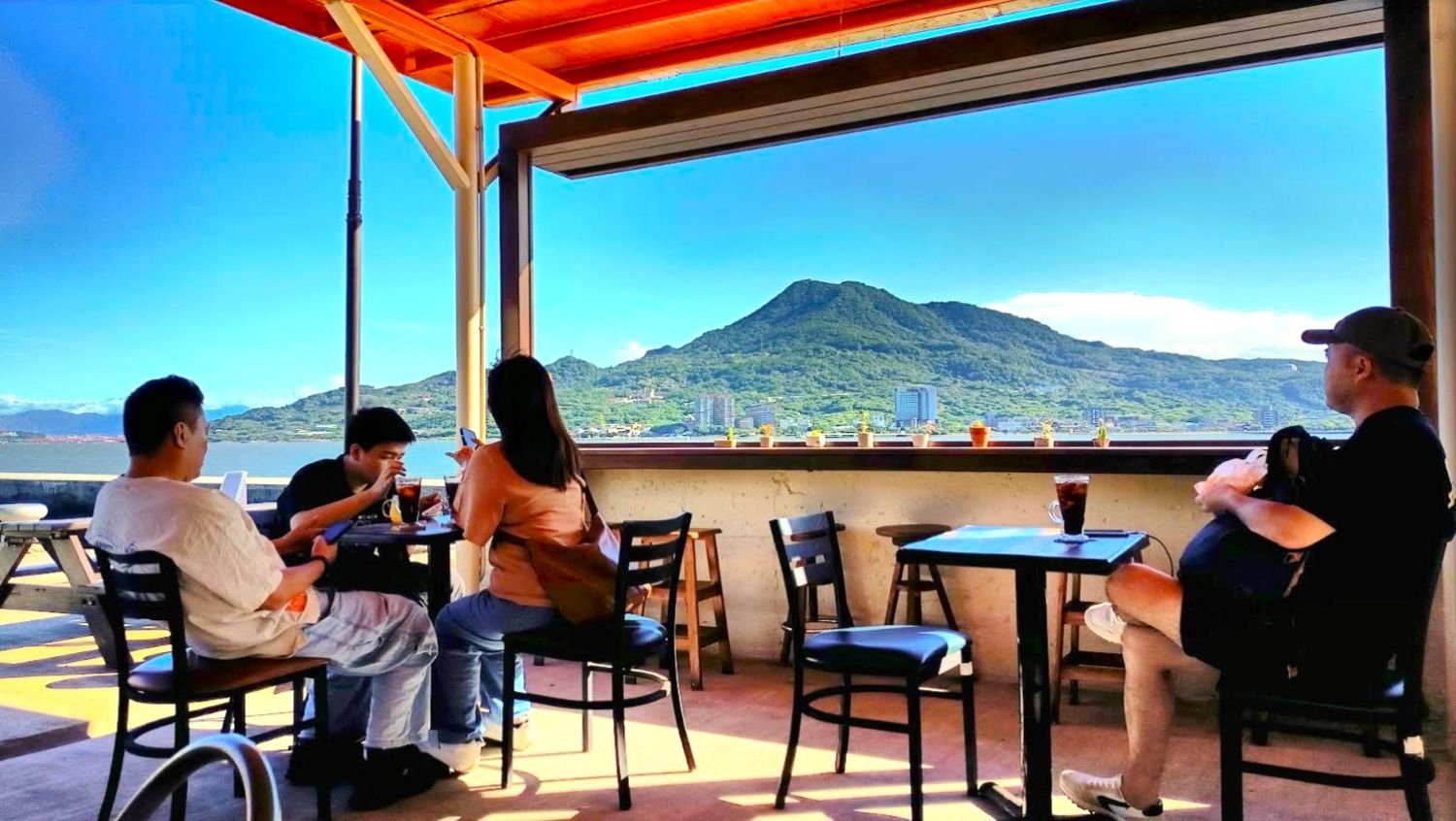 淡水漁文影像館外設有小憩空間邊，邊喝飲品邊欣賞山河美景(陳耀旭館長提供)