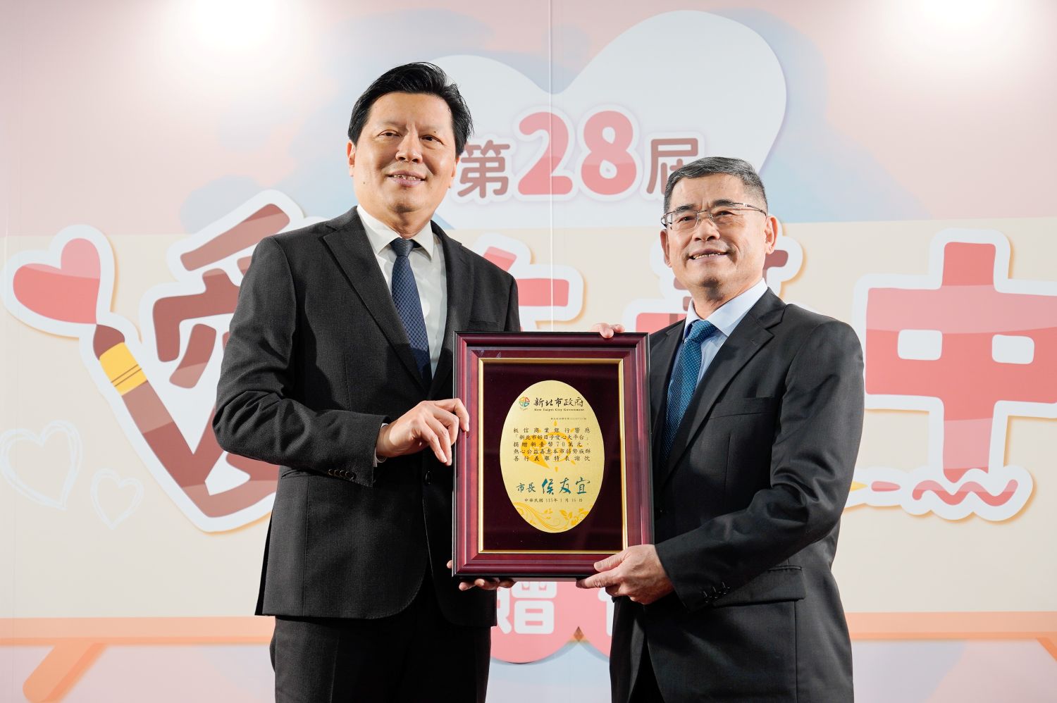 板信商業銀行總經理曾學智(右)代表捐贈70萬元支持「愛在畫中」計畫,新北市副市長朱惕之(左)頒贈感謝牌,感謝板信商銀多年來攜手市府推動公益。