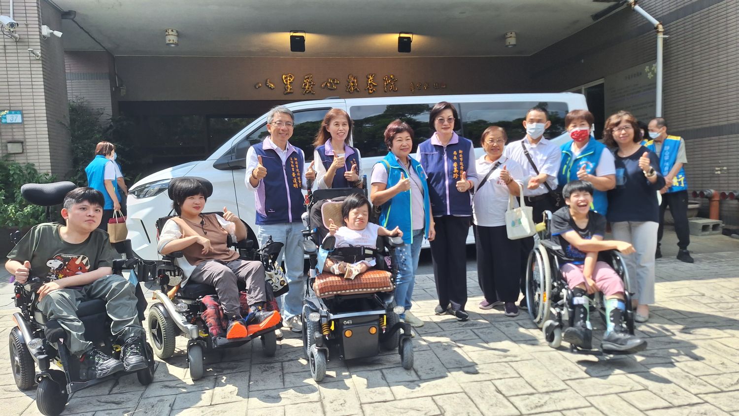林季臻(後排右2)熱心公益,同時是五股靜心院住持的他,號召信徒共同捐贈復康福祉車。2日於八愛舉辦捐贈儀式,由社會局長李美珍代表受贈(後排左4)。其中捐贈者中有一位捐贈者信徒張程凱(後排右3)也是腦麻患者,知道此次捐贈對象後感到格外有意義。